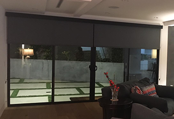 Motorized roller shades installed on patio door in San Francisco living room.