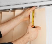 A man installing vertical blinds